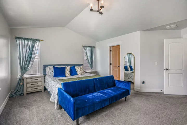 Vaulted ceiling, two windows with blinds, recessed lighting, carpeted flooring, and a white paneled door
