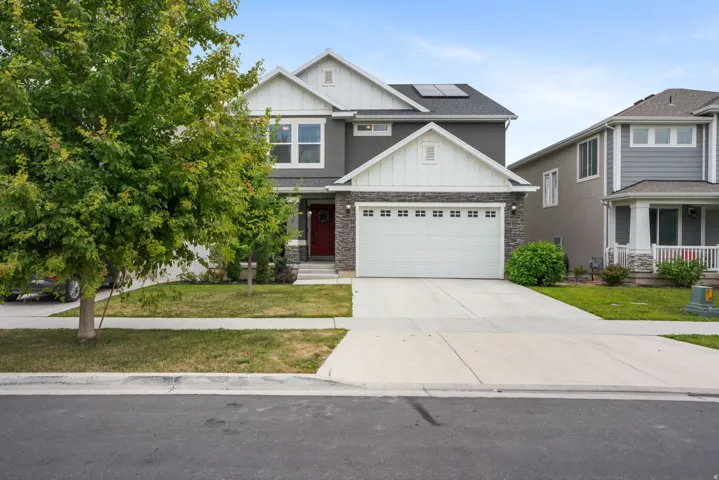 Contemporary two-story exterior with a two-car garage, stone and stucco facade, and a prominent red entry door