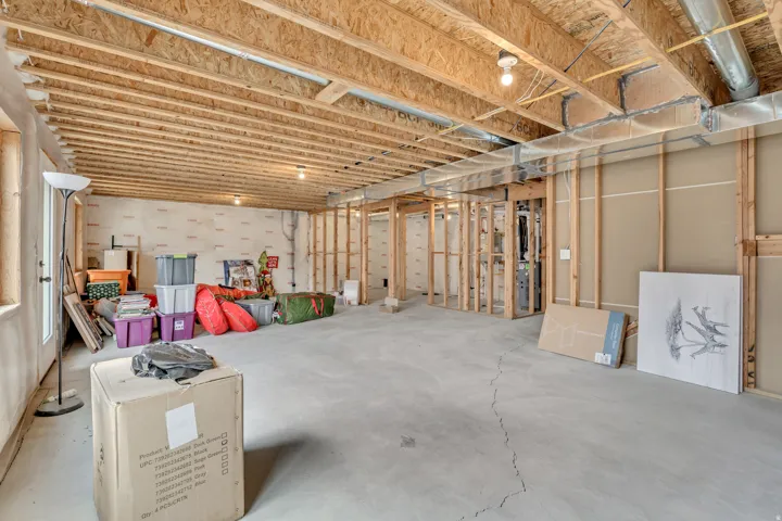 Unfinished basement featuring exposed wood joists, concrete flooring, and framed interior walls