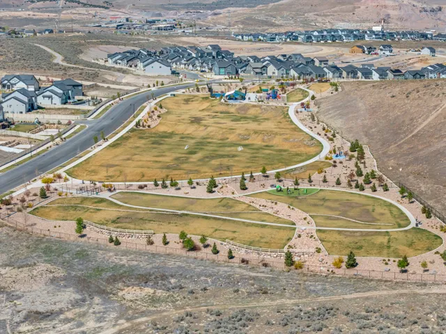 Community green space featuring multiple play areas, paved pathways, and landscaped rock beds