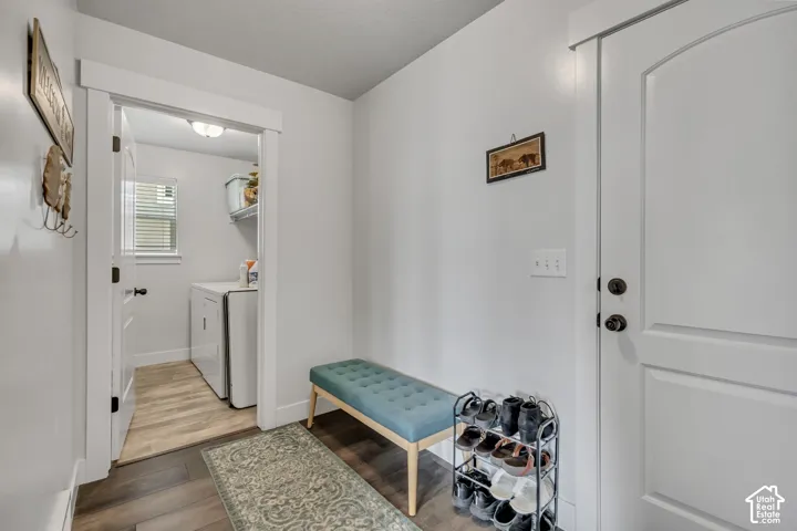 Dedicated laundry area with a window and upper shelving, featuring wood-finish flooring