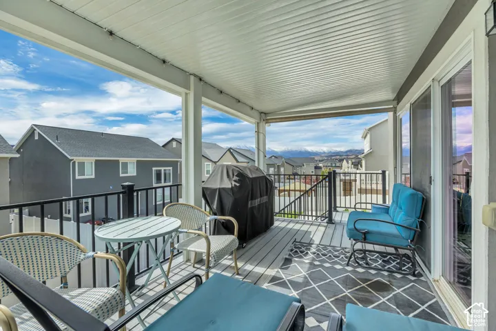 Covered outdoor deck with ceiling panels, a black metal railing, and sliding glass doors