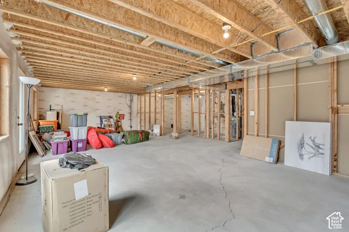 Unfinished basement featuring exposed wood joists, concrete flooring, and framed interior walls