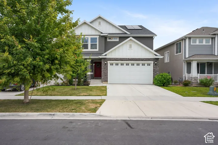 Contemporary two-story exterior with a two-car garage, stone and stucco facade, and a prominent red entry door