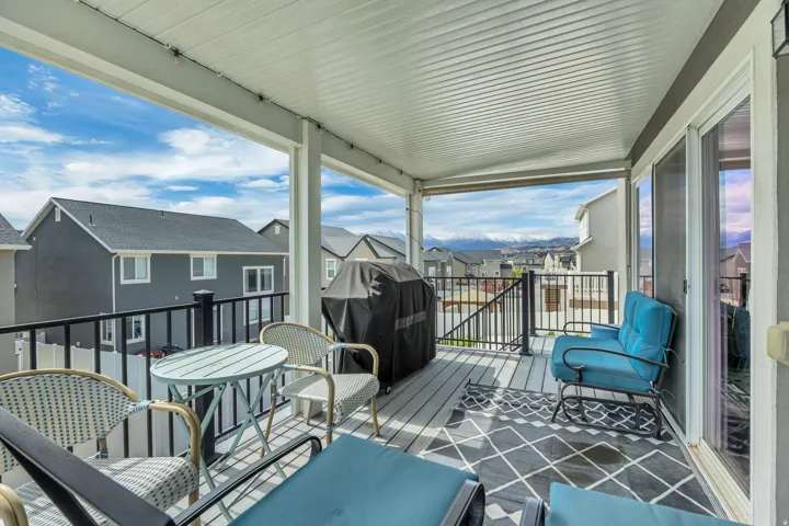 Covered outdoor deck with ceiling panels, a black metal railing, and sliding glass doors