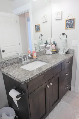 Wood-finish vanity with an integrated sink, polished chrome faucet, and stone-finish countertop