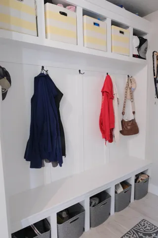 Built-in mudroom bench with storage cubbies, upper shelving, and wall-mounted hooks