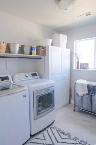 Laundry area featuring a built-in shelf, white cabinetry, and light-colored flooring