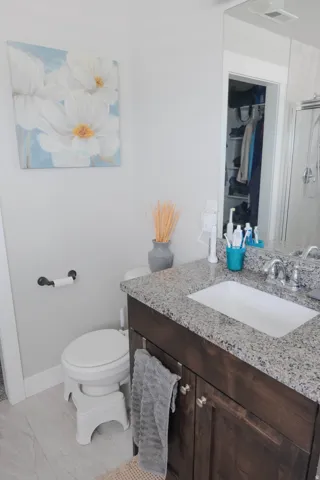 Vanity with a granite-finish countertop, undermount sink, and wood-finish cabinetry