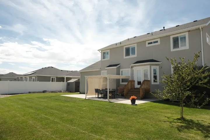 Expansive backyard with a manicured lawn, a large concrete patio, and a dedicated outdoor dining area