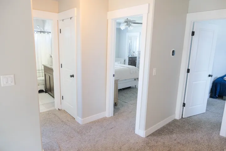 Light gray wall paint, white trim, white interior doors with dark hardware, and light-colored carpet flooring