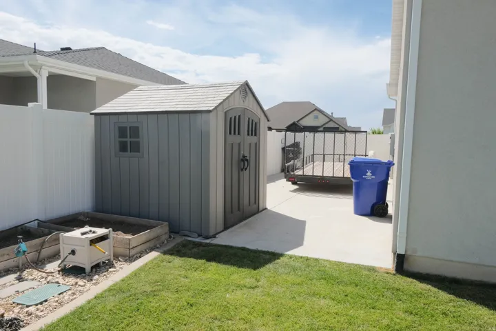 Private backyard featuring a shed, raised garden beds, and a concrete patio