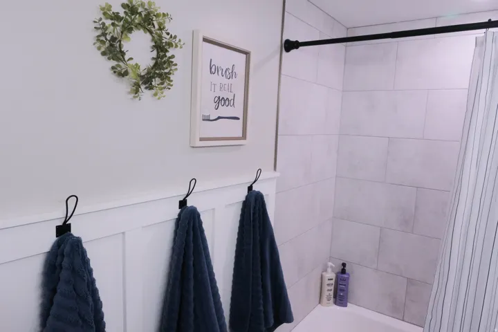 White subway tile shower surround with black shower rod and a white bathtub
