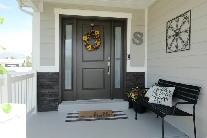 Front entry with a dark-paneled door, two vertical sidelight windows, and a stacked stone accent wall