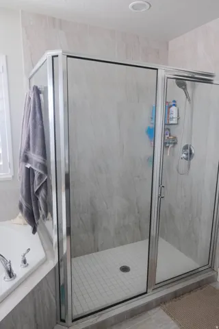 Glass-enclosed shower with a tiled floor, chrome fixtures, and surrounding tile work
