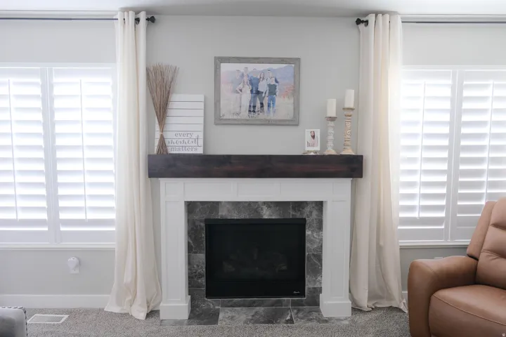 Fireplace featuring a dark wood-finish mantel and stone surround