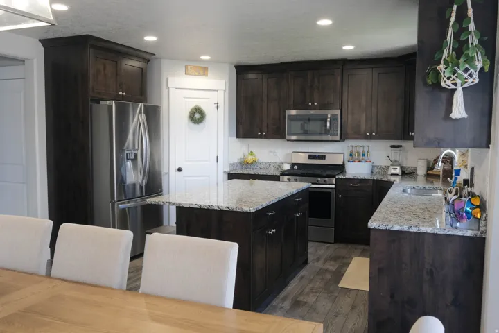 Kitchen featuring dark wood-finish cabinetry, light speckled countertops, a stainless steel refrigerator, a stainless steel range, and a stainless steel microwave