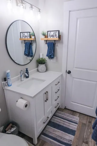 White vanity with brushed nickel hardware, integrated sink, and coordinated wall-mounted lighting