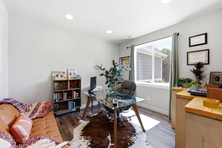 Recessed lighting illuminates the space, featuring wood-finish flooring and a large window