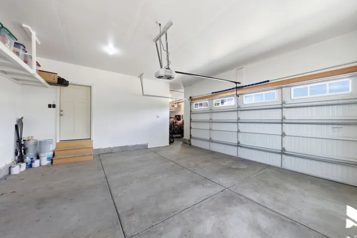Attached garage featuring a concrete floor, overhead storage shelving, and a paneled garage door with upper window inserts