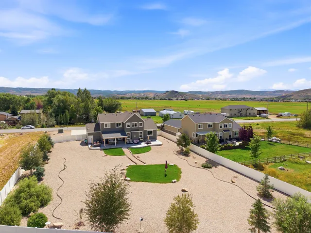 Spacious gravel yard with dedicated grassy areas, mature trees, and privacy fencing