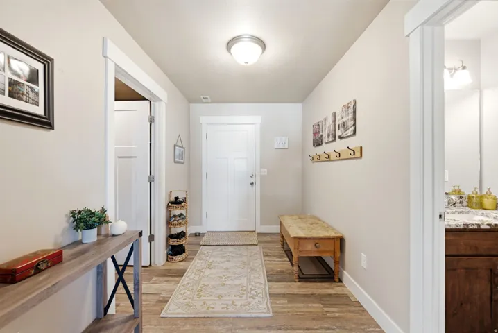 Wood-finish flooring, white trim, recessed lighting, and a solid white front door