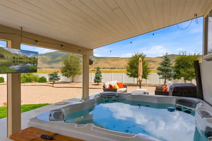 Covered patio with an integrated hot tub and mounted exterior television