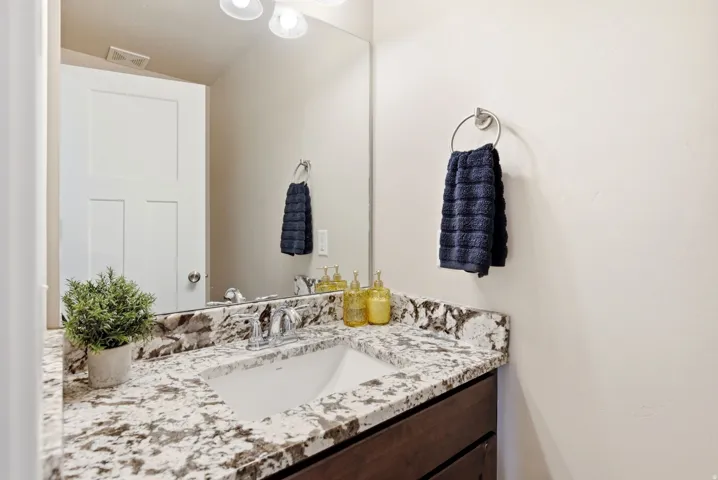 Vanity with a polished chrome faucet, under-mount sink, and speckled stone countertop