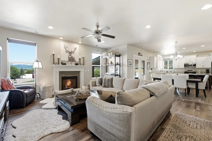 Open-concept interior featuring wood-finish flooring, a fireplace with a mantel, recessed lighting, and a ceiling fan
