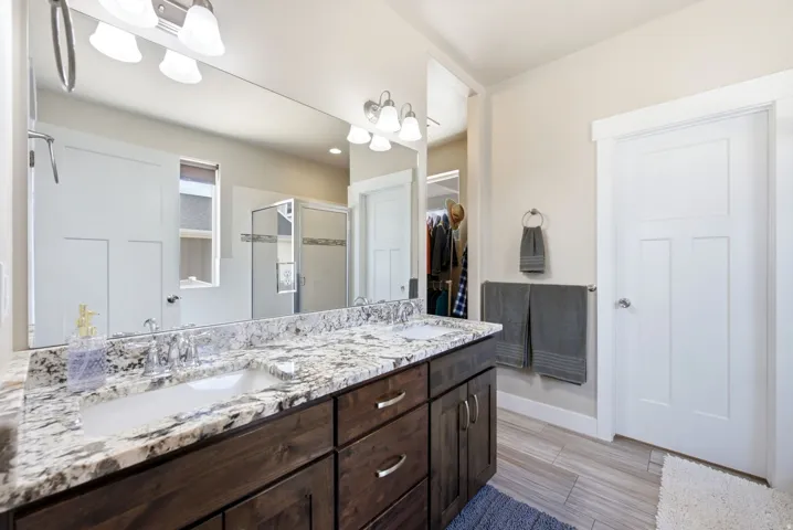 Dual vanity with a stone countertop, undermount sinks, and wood-finish cabinetry