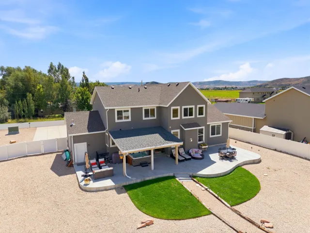 Spacious backyard with a large concrete patio, covered patio area, manicured lawn, and gravel landscaping