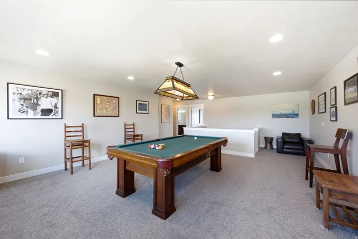 Recessed lighting, wood-finish pool table, and a decorative pendant light fixture