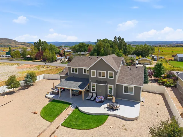 Two-story property with a covered patio, multiple windows, and a large concrete patio