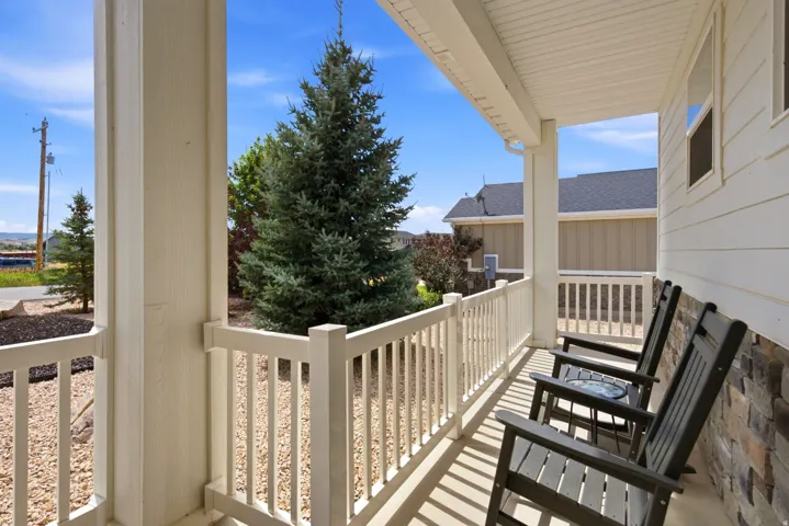 Covered front porch featuring white railings, stone veneer accents, and horizontal siding
