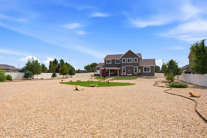Expansive gravel yard with a dedicated grassy area and mature trees