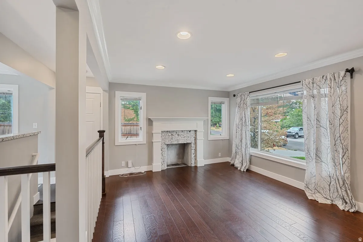 Hardwood flooring, recessed lighting, crown molding, a fireplace with a white mantel, and multiple windows