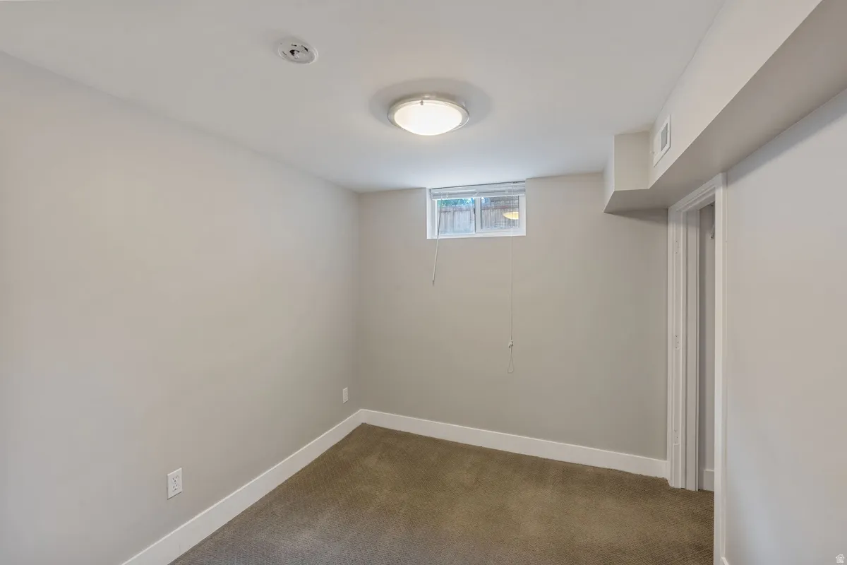 Room featuring light gray painted walls, brown carpet flooring, and a white trim