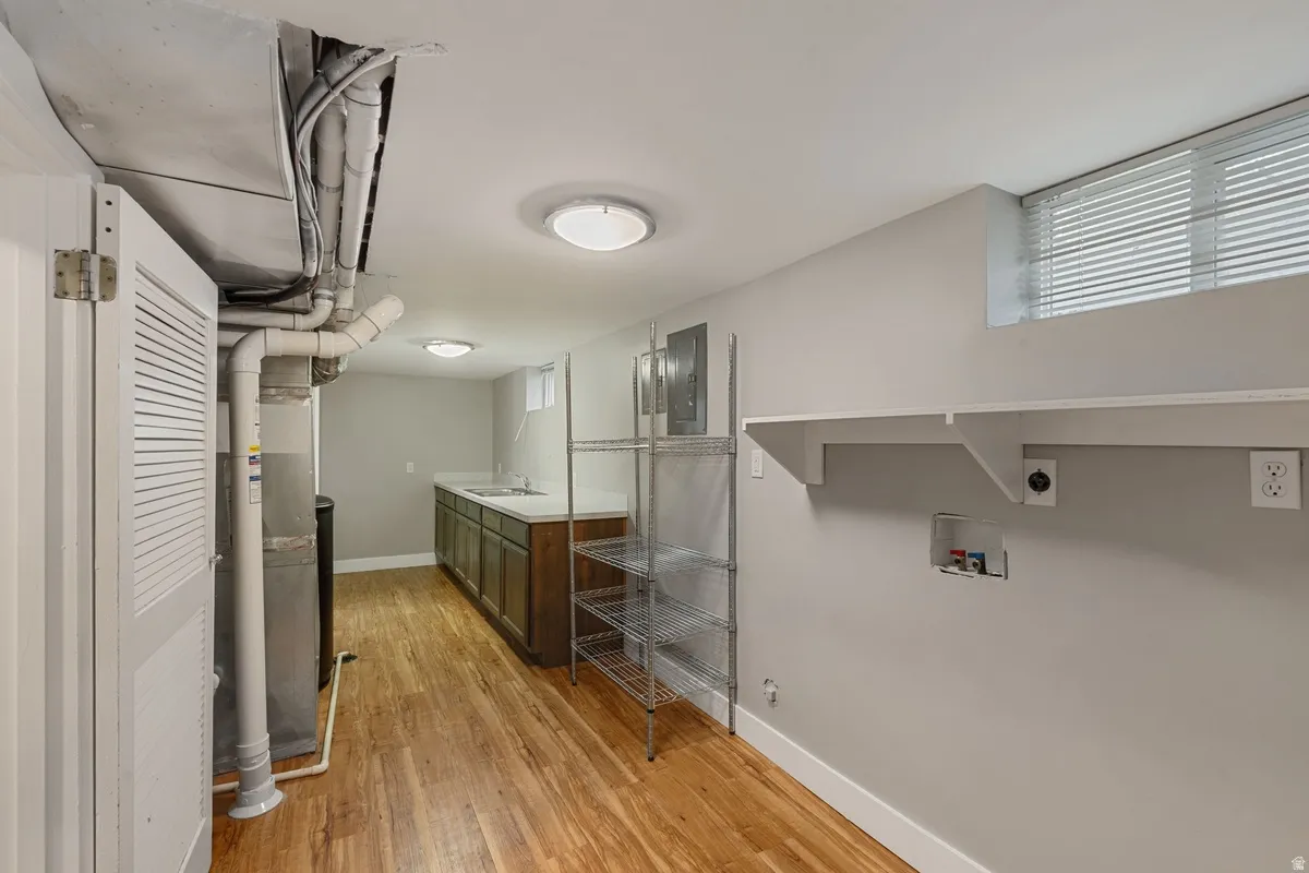 Wood-finish flooring, recessed lighting, built-in shelving, utility sink, and a window with blinds