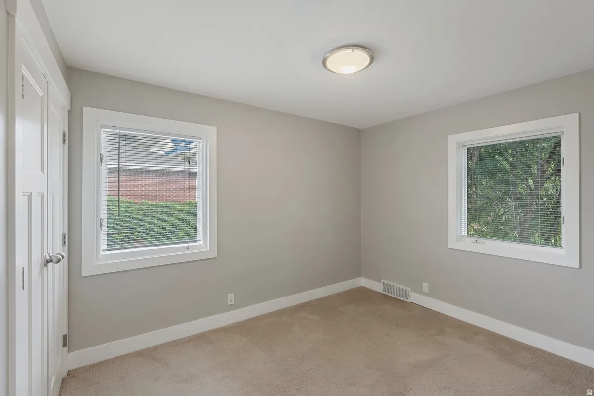 Soft neutral wall paint, two windows with white trim, and a flush-mount ceiling light