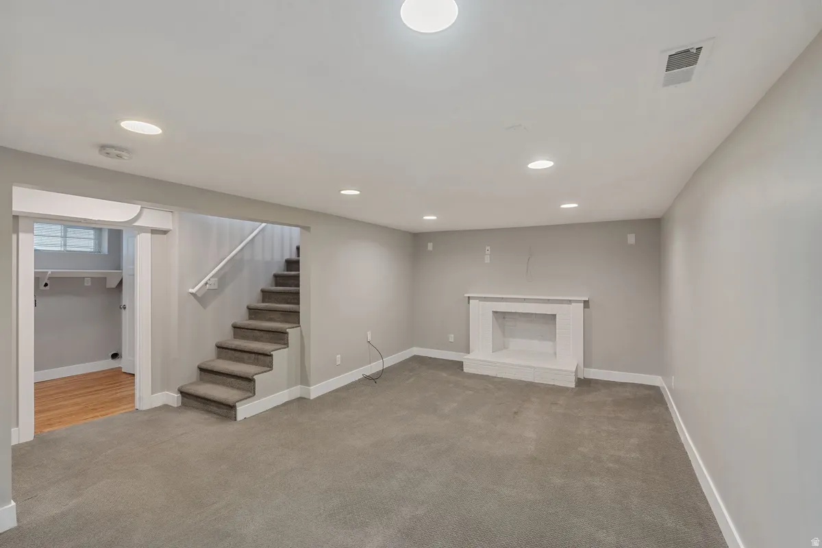 Recessed lighting, neutral wall paint, carpeted flooring, finished fireplace, and wood-finish flooring in an adjoining room