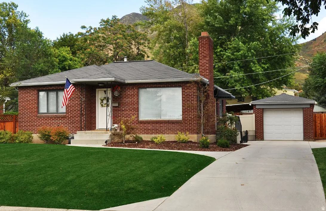Brick exterior with a prominent chimney, a detached garage, and a concrete driveway