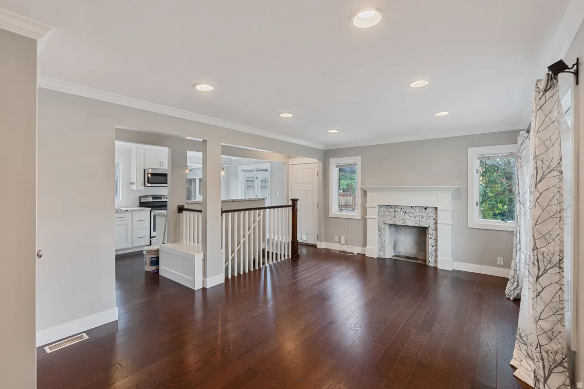 Spacious interior with dark wood-finish flooring, recessed lighting, and crown molding