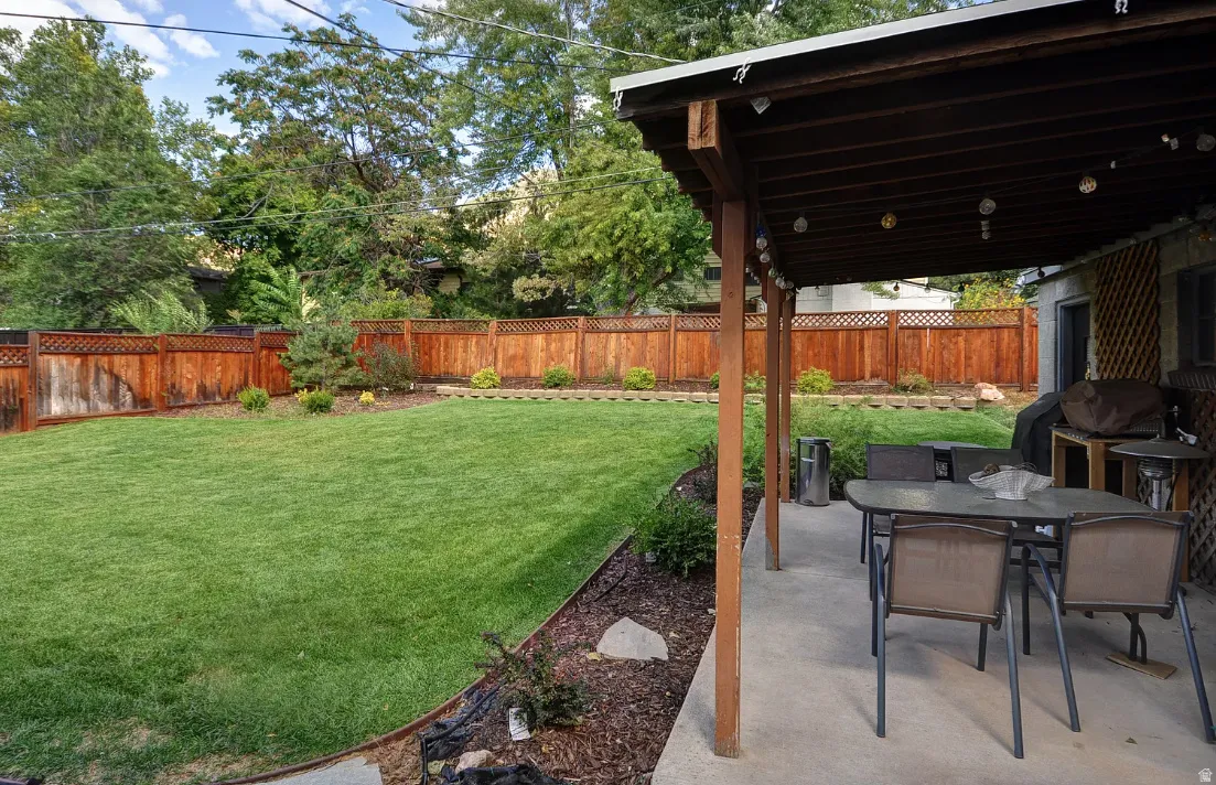Expansive backyard featuring a lush lawn, wood fencing, and mature trees
