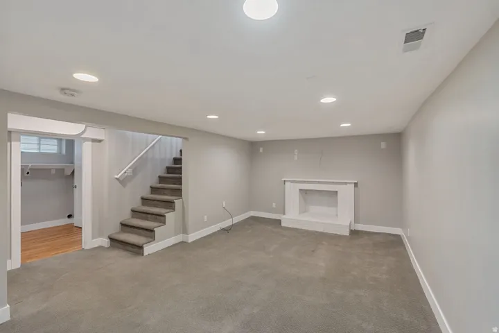 Recessed lighting, neutral wall paint, carpeted flooring, finished fireplace, and wood-finish flooring in an adjoining room