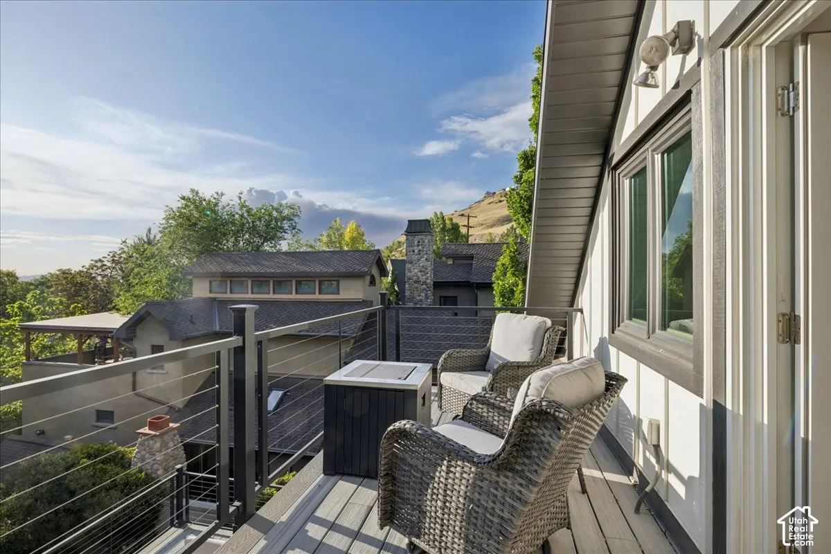 Exterior deck featuring composite wood-finish decking, dark gray cable railings, and a white vertical board and batten siding