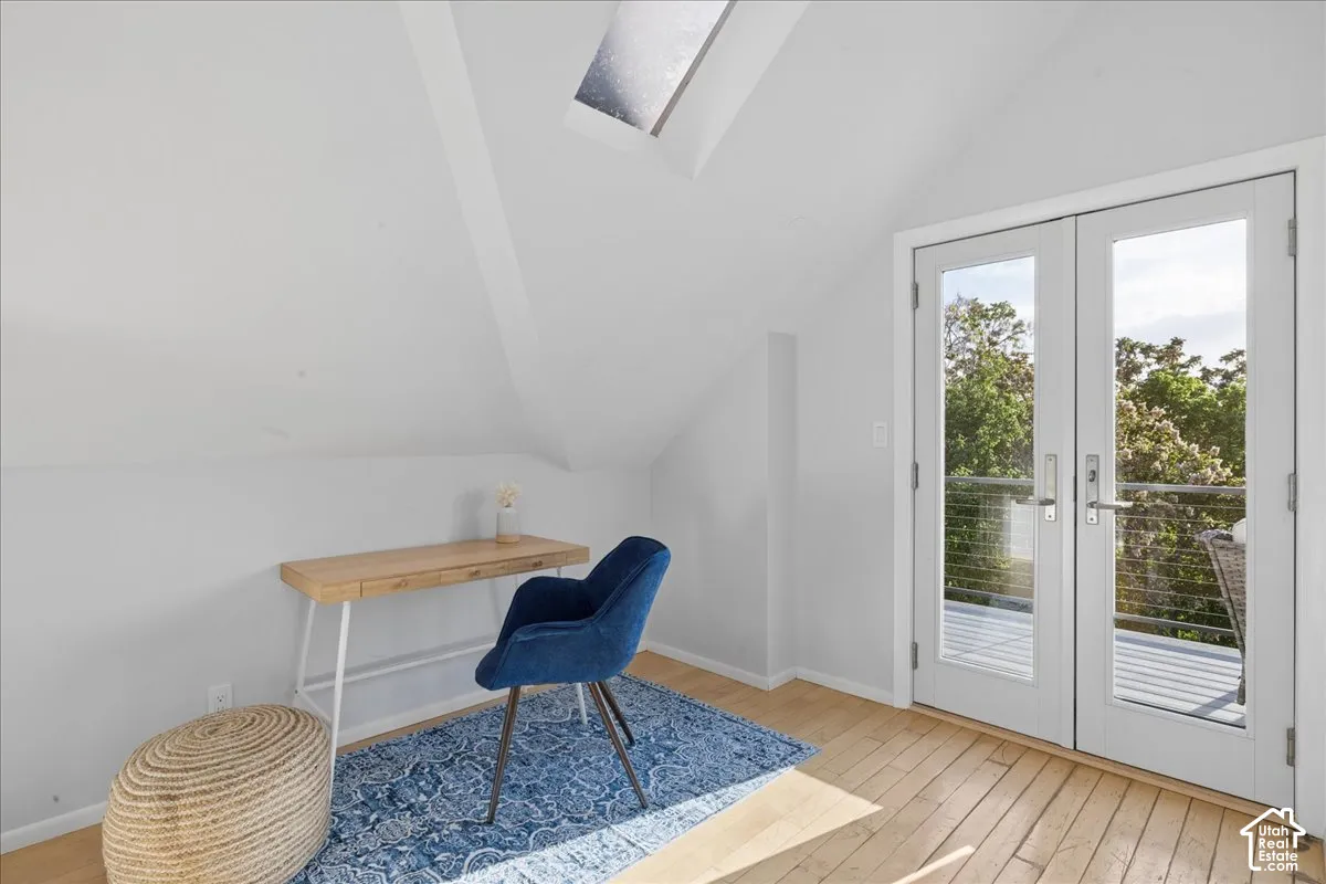 Attic room featuring a skylight, light wood-finish flooring, and bright white walls