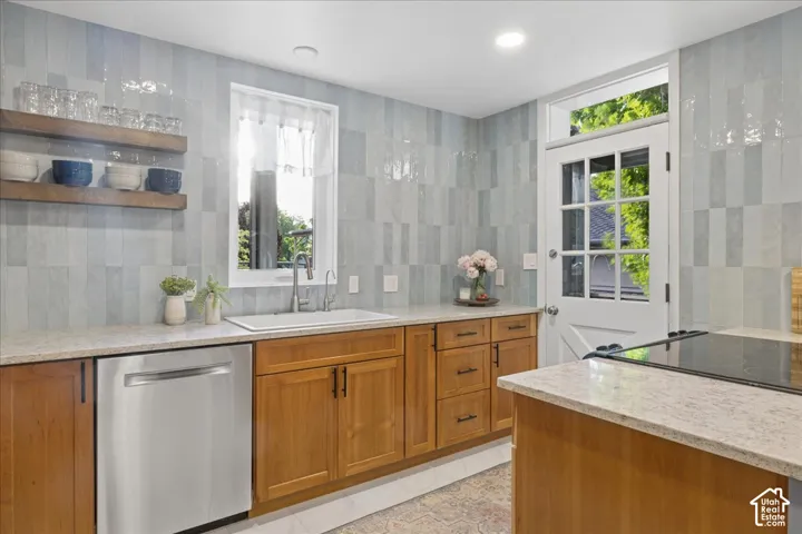 Kitchen featuring light wood cabinetry, light-toned countertops, a stainless steel dishwasher, a white single-basin sink with a gooseneck faucet, and light blue subway tile backsplash