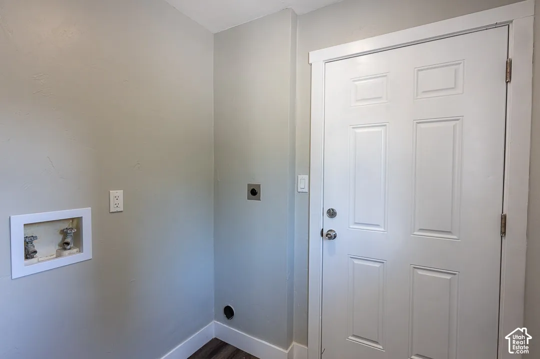 Dedicated laundry area with a white paneled door, gray wall finish, and wood-finish flooring