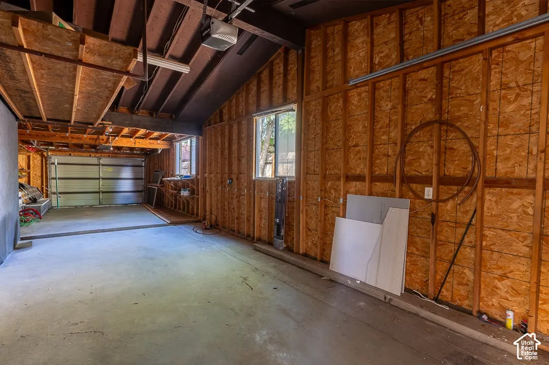 Spacious garage area featuring a concrete floor, exposed wood beam ceiling, and two windows