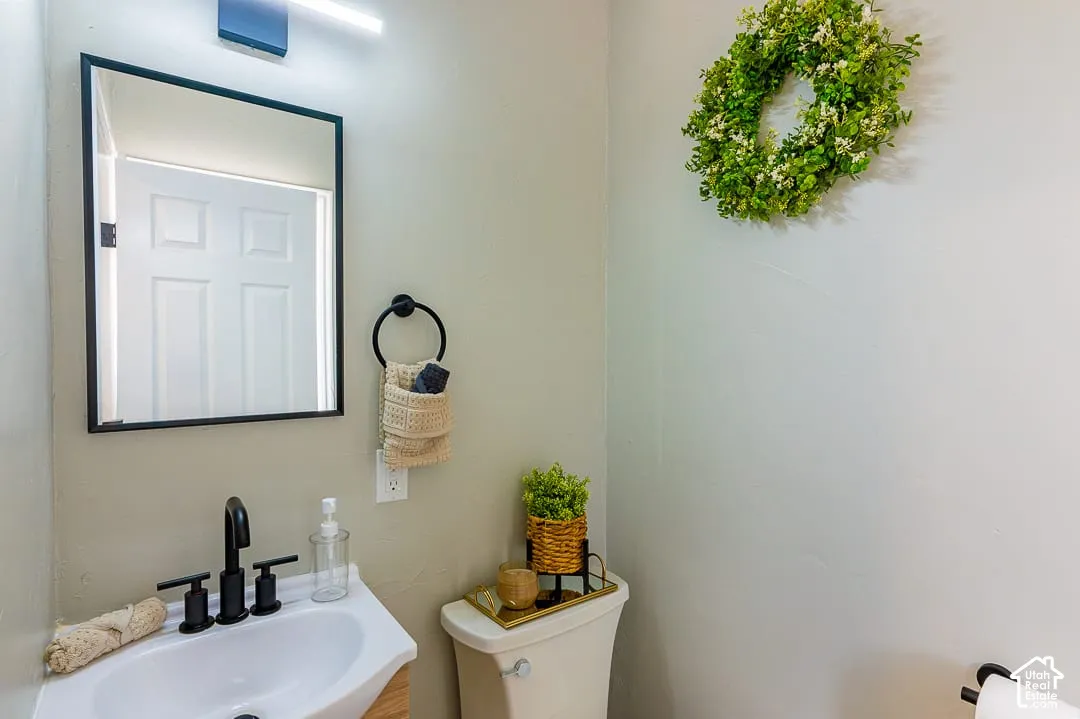 White wall-mounted sink with matte black faucet, framed vanity mirror, and linear light fixture